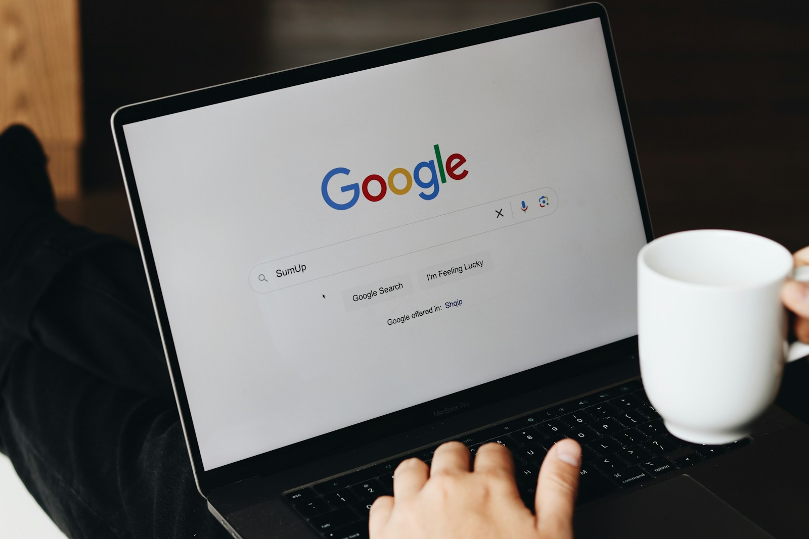 Person searching on Google using a laptop at a desk