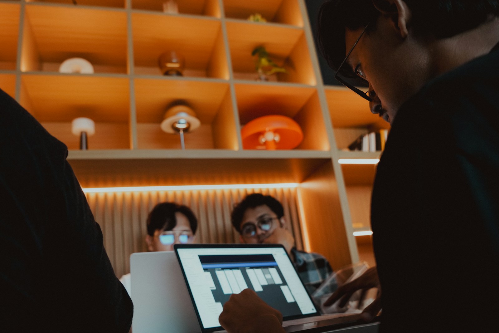 Design team collaborating around a laptop in a warm modern studio