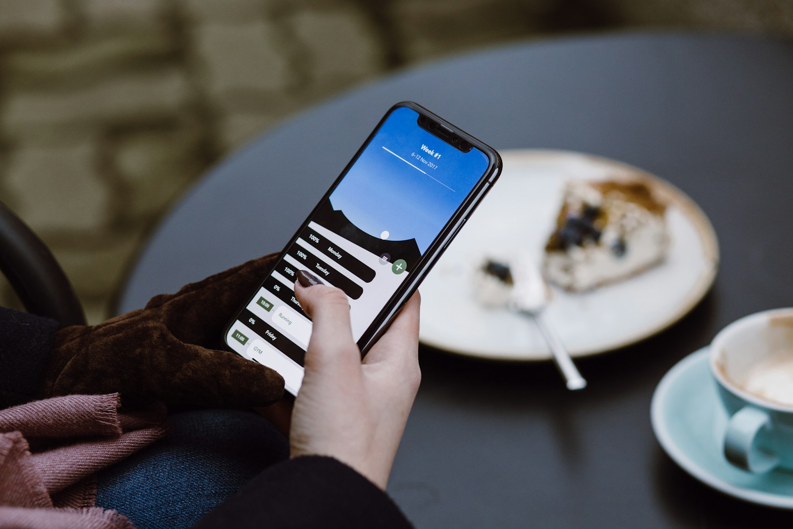 Person using a smartphone at a café table with shallow depth of field