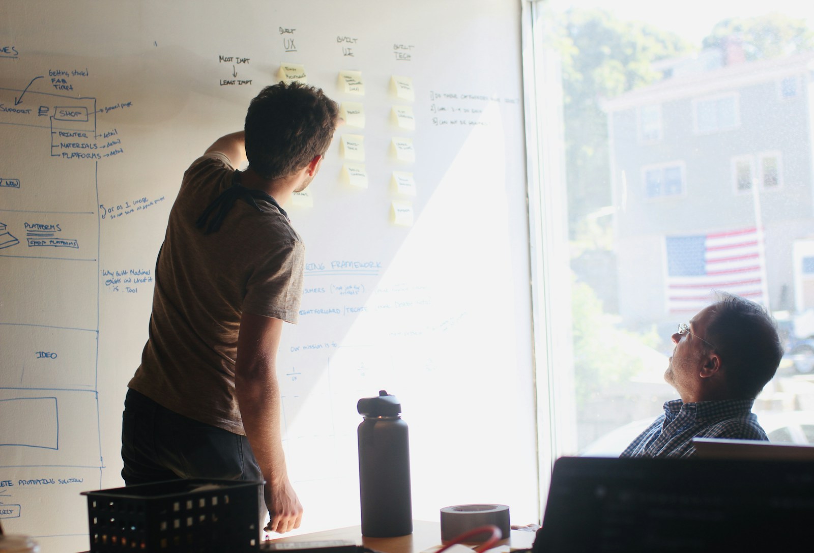 Designer presenting a UI wireframe on a whiteboard to a colleague
